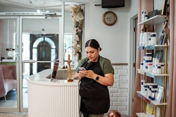 Perakende ürün raflarının yanında telefon kullanan salon profesyoneli